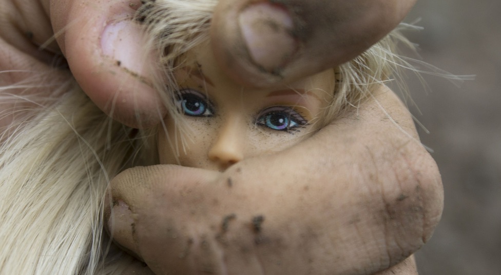 Una mano stringe una bambola: violenza sulla donna. L'aborto è violenza sulla donna
